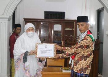 Fitri Nora serahkan bantuan kepada Elwi Yandri pengurus masjid Darul Muttaqin.